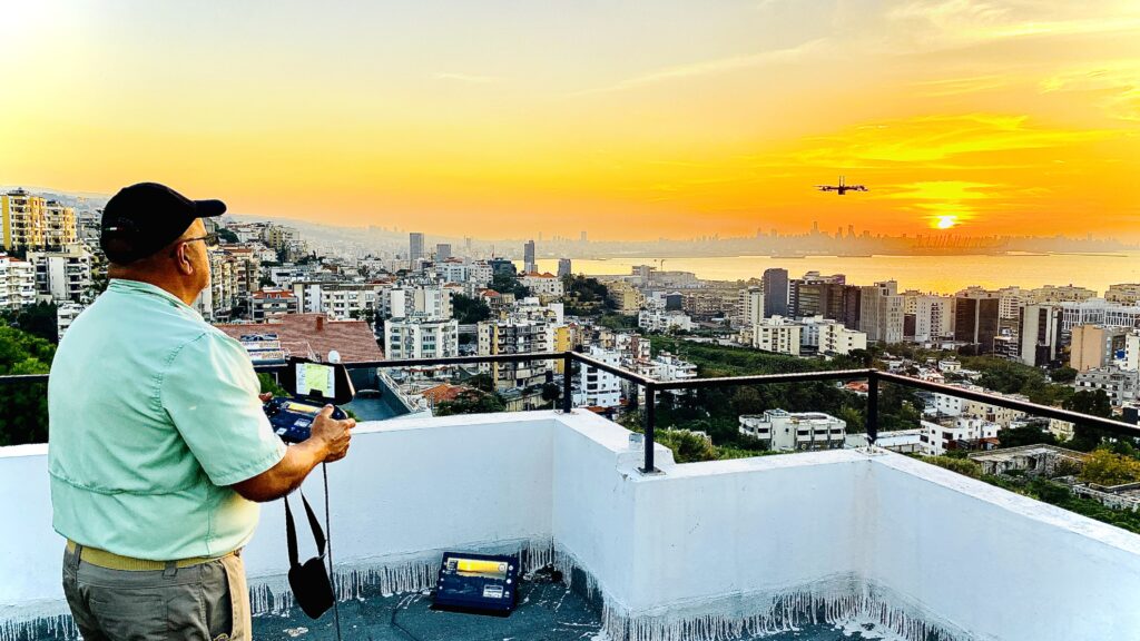 Otto Fernandez standing on a rooftop with a drone flying over a city